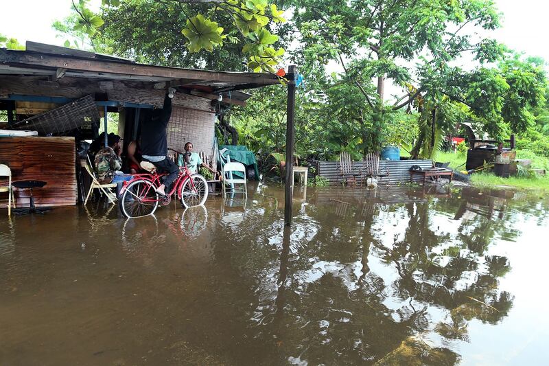 Cinco hombres aparecen sentados y con el agua hasta los tobillos por las inundaciones provocadas por el huracán Fiona.