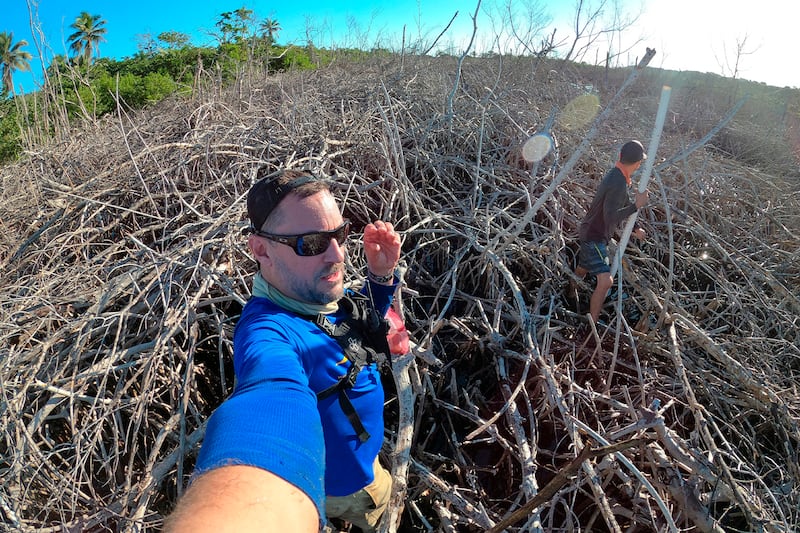 El doctor Robert. Mayer y José Vera caminan entre mangles rojos muertos. Uno de ellos sostiene la cámara a modo de 'selfie'.