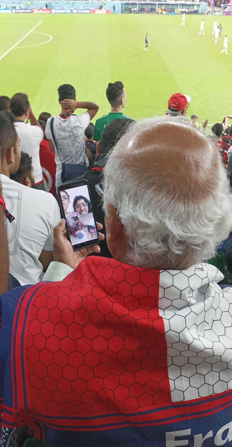 Narin observa su teléfono celular desde las gradas del estadio de fútbol en Doha en medio de una videollamada con varios de sus familiares.