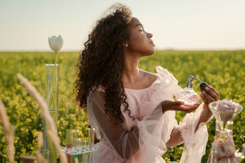 Mujer perfumándose al aire libre