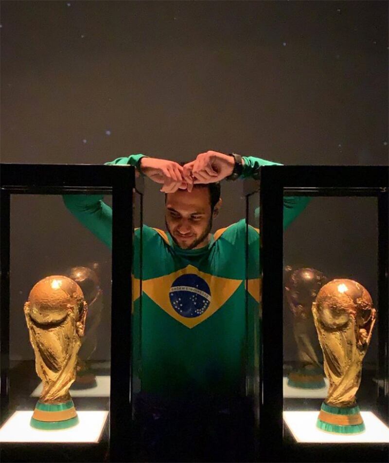 El personaje Supermano observa dos copas de fútbol.