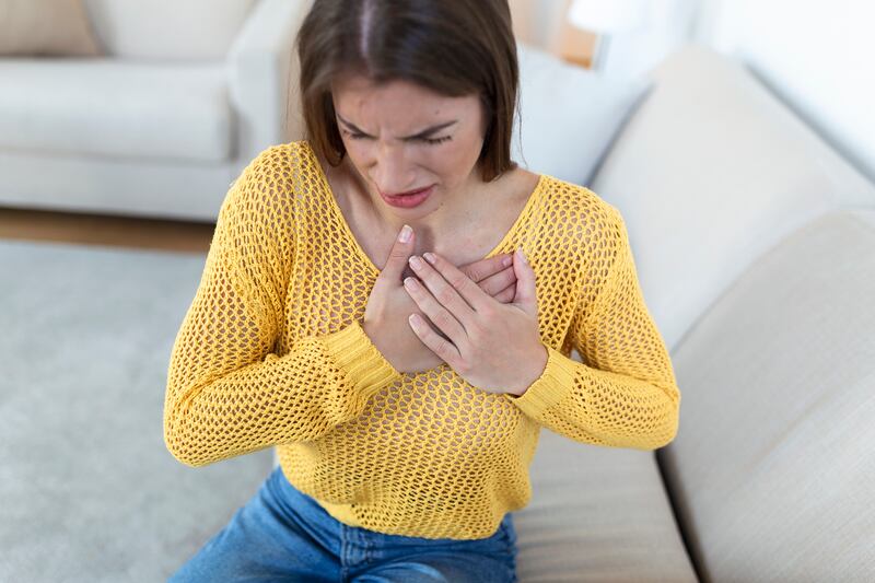 Mulher jovem com a mão no peito sentido infarto