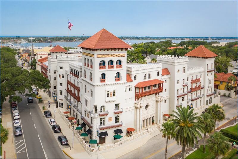 Un edificio de estilo colonial hace esquina entre dos calles. Al fondo tiene el mar.