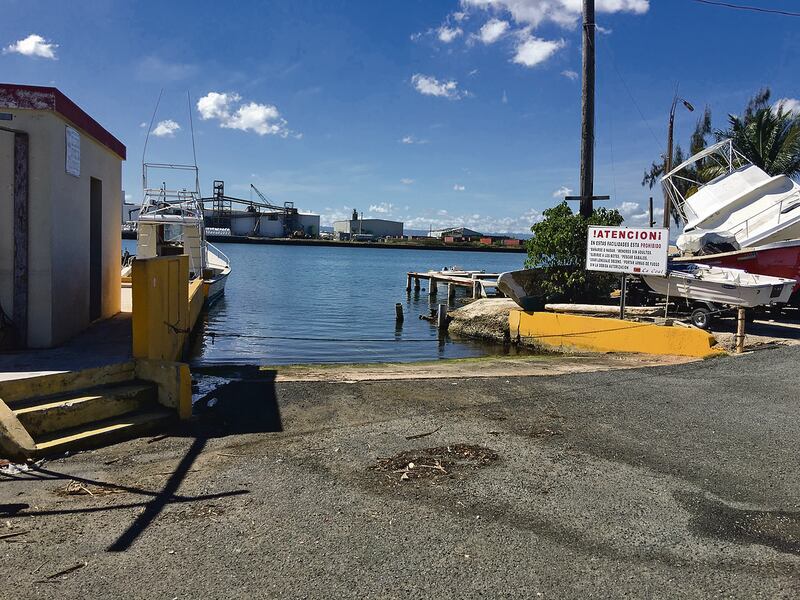 Una entrada al cuerpo de agua en el muelle, con una estructura humilde a la izquierda y embarcaciones pequeñas estacionadas a la derecha.