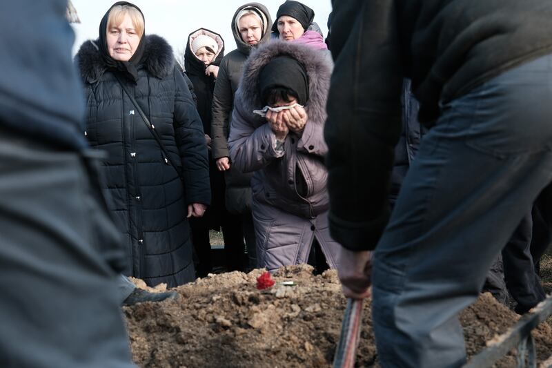 Una mujer llora mientras el ataúd del soldado ucraniano Sergiy Sochenko es colocado en la tierra.