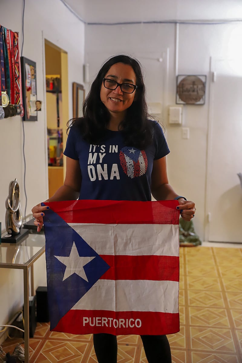 Kisha Cedeño sostiene una bandera puertorriqueña, uno de los muchos objetos en su hogar que la mantienen conectada con Puerto Rico.